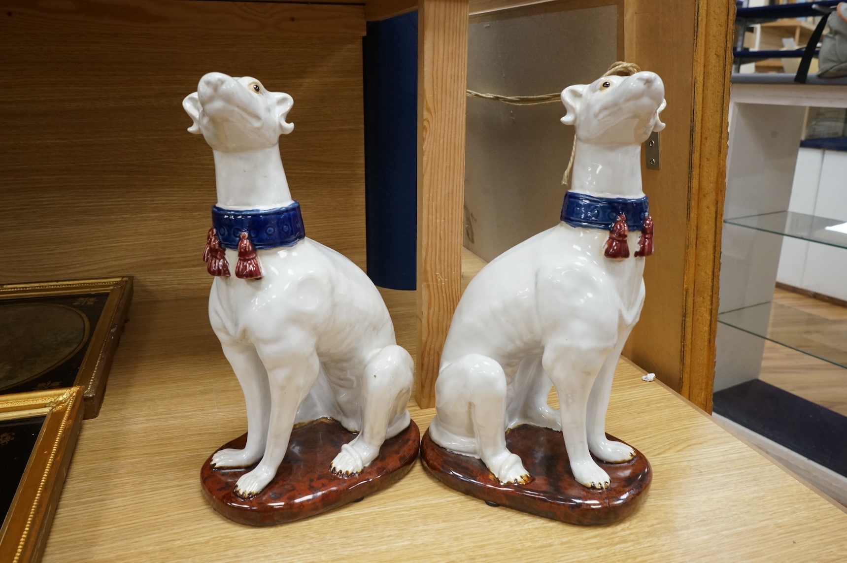 A pair tin glaze models of seated dogs, possibly Greyhounds. 36cm high.